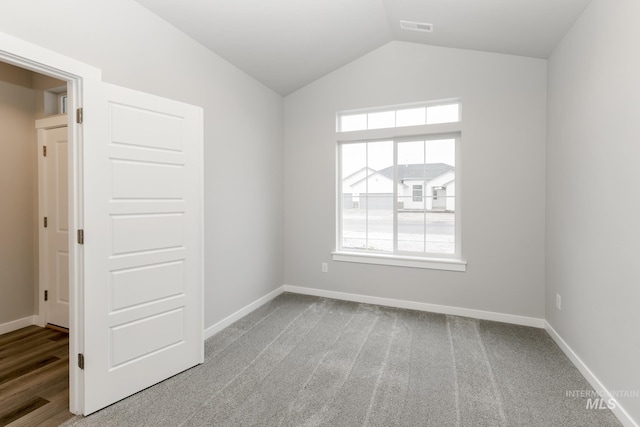 unfurnished room with vaulted ceiling, baseboards, visible vents, and carpet floors