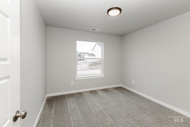 spare room featuring carpet flooring, visible vents, and baseboards