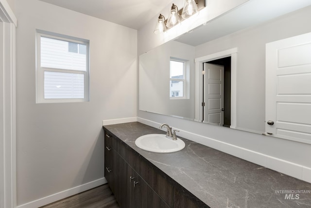 bathroom with vanity, wood finished floors, and baseboards