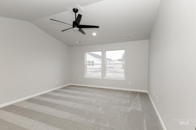 spare room featuring visible vents, a ceiling fan, baseboards, light colored carpet, and vaulted ceiling