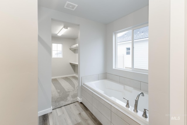 full bath featuring wood finished floors, visible vents, baseboards, and a bath