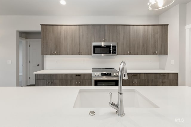 kitchen featuring a sink, modern cabinets, appliances with stainless steel finishes, and light countertops