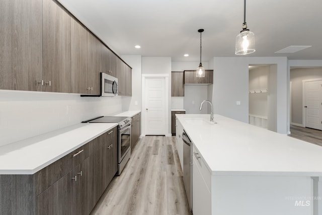 kitchen with modern cabinets, light wood-style floors, appliances with stainless steel finishes, and a sink