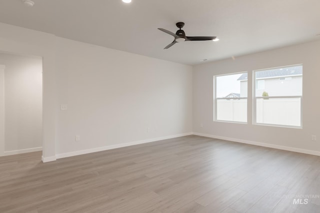 unfurnished room with a ceiling fan, light wood-type flooring, and baseboards