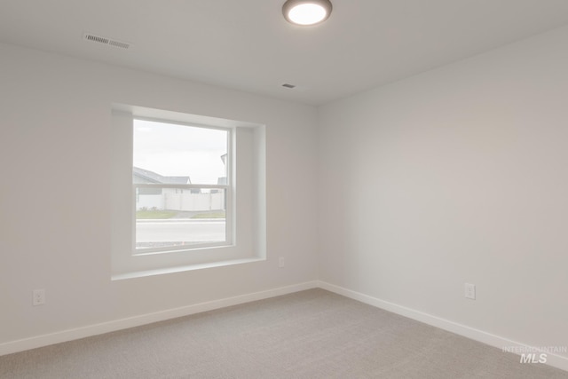 empty room featuring visible vents, light carpet, and baseboards