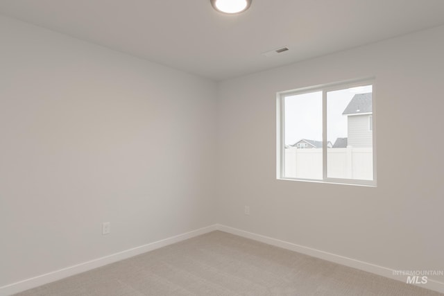 spare room with light carpet, visible vents, and baseboards