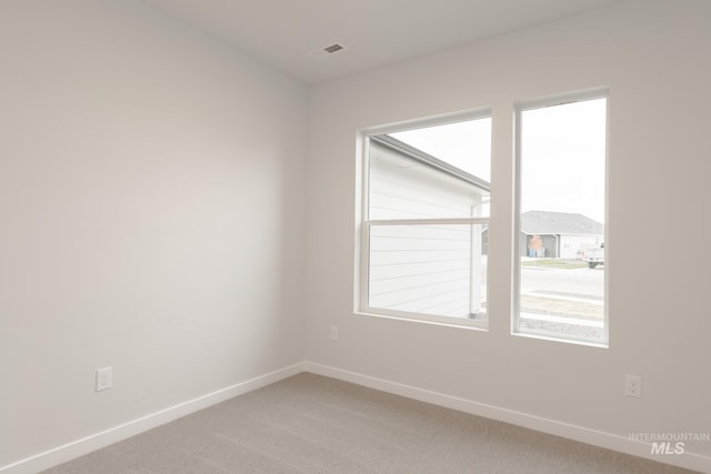 empty room featuring visible vents, baseboards, and light colored carpet