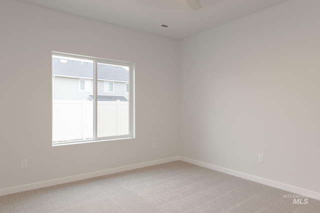 spare room featuring light carpet and baseboards