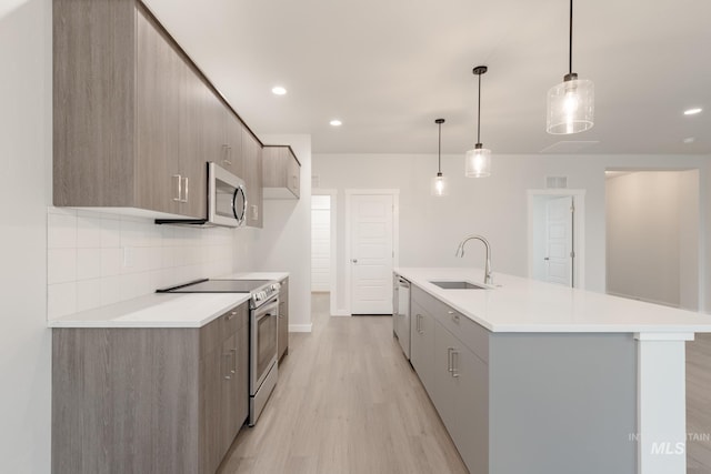 kitchen featuring light wood-type flooring, modern cabinets, a sink, stainless steel appliances, and light countertops