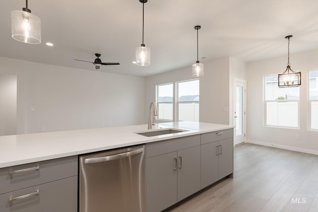 kitchen with gray cabinets, a sink, light countertops, light wood-style floors, and stainless steel dishwasher