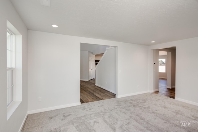 carpeted spare room featuring a textured ceiling, recessed lighting, visible vents, and baseboards