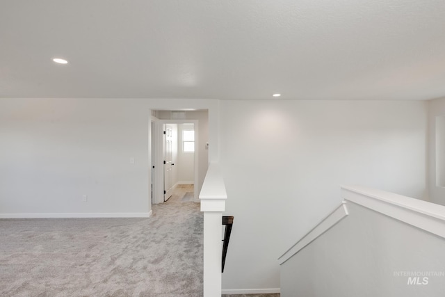 corridor featuring recessed lighting, baseboards, light carpet, and an upstairs landing