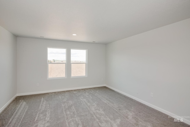 empty room featuring recessed lighting, light colored carpet, and baseboards