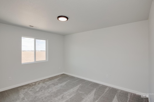 spare room featuring light carpet, visible vents, and baseboards