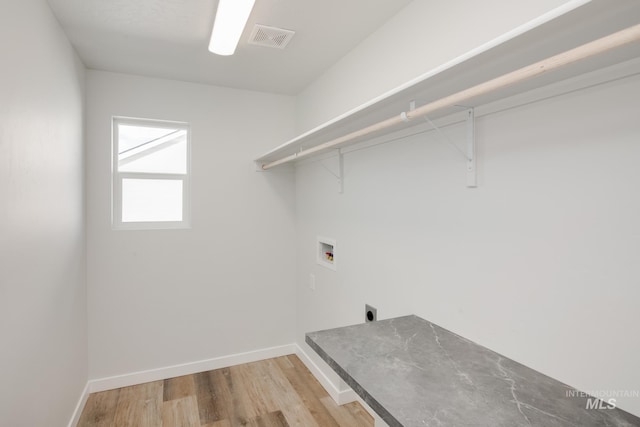 clothes washing area with laundry area, visible vents, baseboards, wood finished floors, and washer hookup