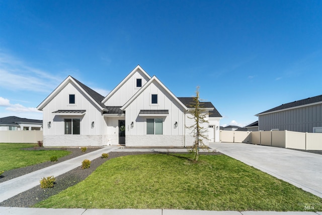 modern farmhouse featuring driveway, a standing seam roof, board and batten siding, a front yard, and metal roof