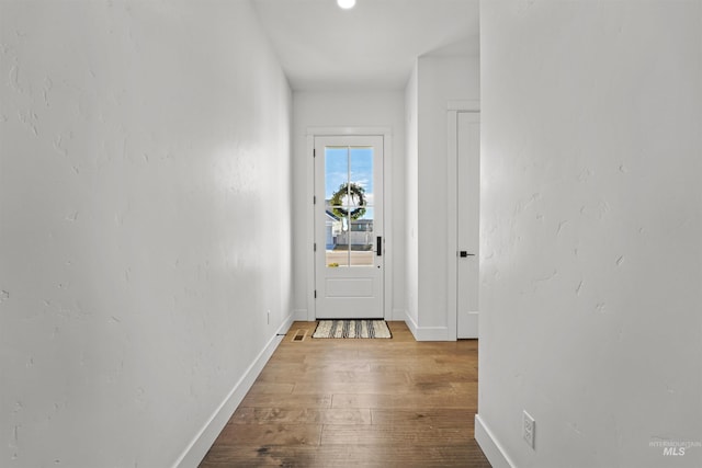 corridor featuring baseboards and wood-type flooring
