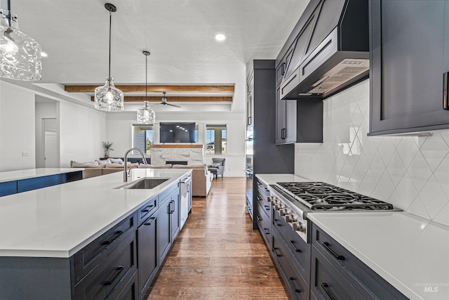 kitchen with backsplash, dark wood-type flooring, open floor plan, wall chimney exhaust hood, and a sink