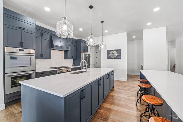kitchen with a breakfast bar area, light wood finished floors, a spacious island, custom exhaust hood, and a sink