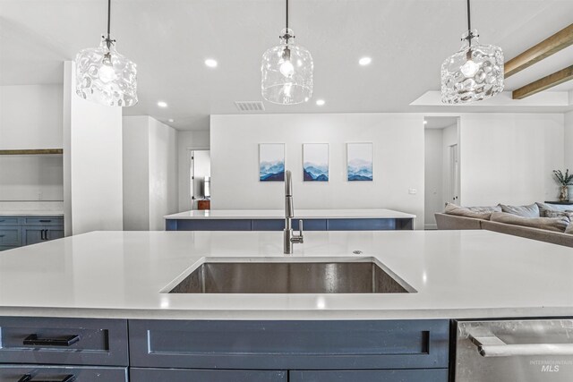 kitchen featuring visible vents, a sink, light countertops, stainless steel dishwasher, and open floor plan
