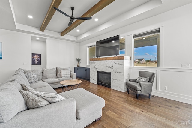 living room featuring wood finished floors, a fireplace, recessed lighting, ceiling fan, and beamed ceiling