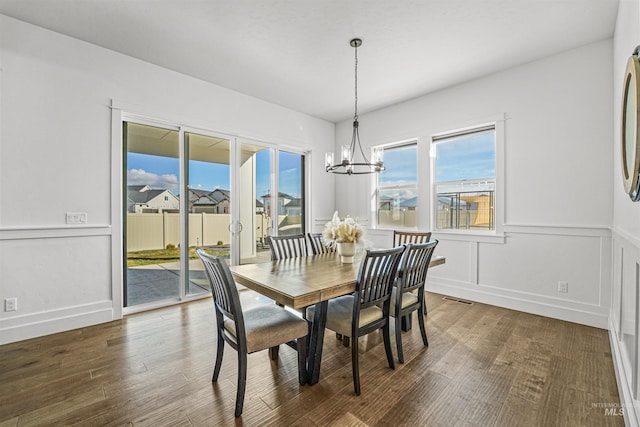 dining space with an inviting chandelier, a decorative wall, wood finished floors, and visible vents