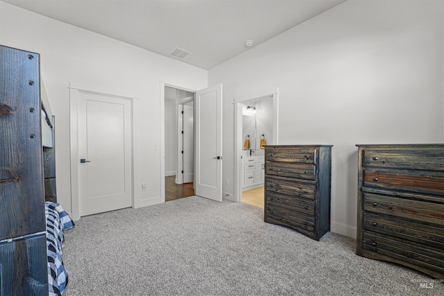 carpeted bedroom with baseboards, visible vents, and ensuite bathroom