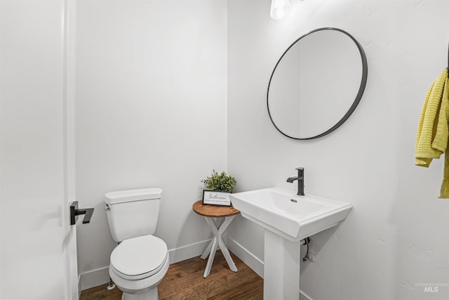 bathroom featuring toilet, wood finished floors, baseboards, and a sink