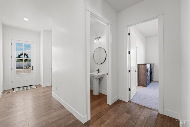 corridor featuring a sink, recessed lighting, baseboards, and wood finished floors
