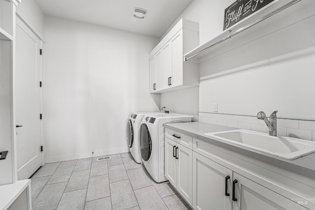 washroom with baseboards, visible vents, separate washer and dryer, cabinet space, and a sink