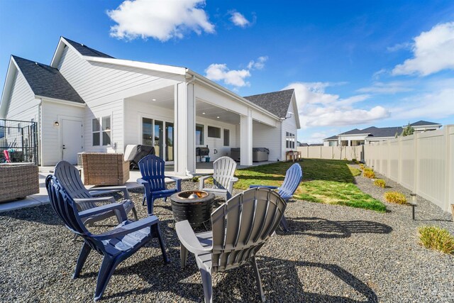 back of property with a patio, a fire pit, roof with shingles, and a fenced backyard