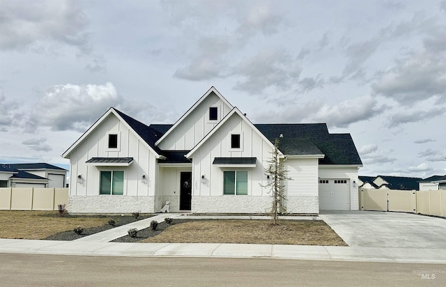 modern farmhouse style home featuring fence, board and batten siding, driveway, and a gate