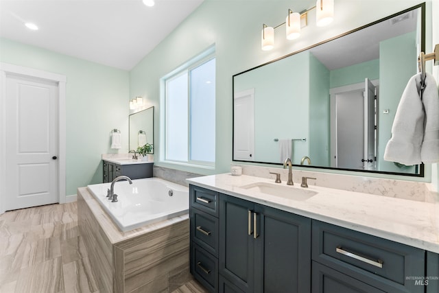 bathroom featuring tiled bath and vanity