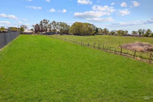 view of yard with fence and a rural view