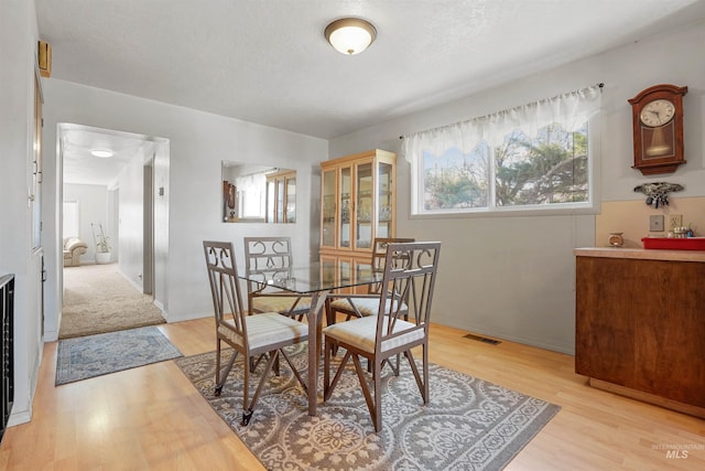 dining space featuring baseboards, light wood finished floors, and visible vents