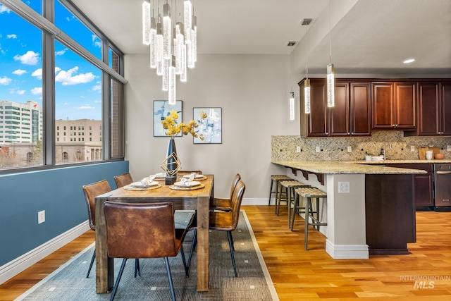 dining space with a notable chandelier, light wood-style flooring, visible vents, and baseboards