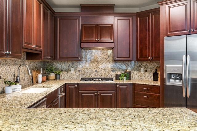 kitchen featuring tasteful backsplash, dark brown cabinets, stainless steel appliances, and a sink