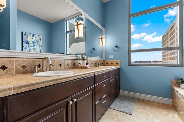 full bath featuring double vanity, decorative backsplash, baseboards, and a sink