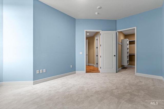 unfurnished bedroom with baseboards, carpet, and a spacious closet