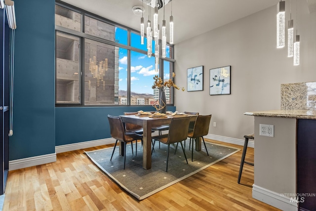 dining space featuring baseboards, a notable chandelier, and wood finished floors