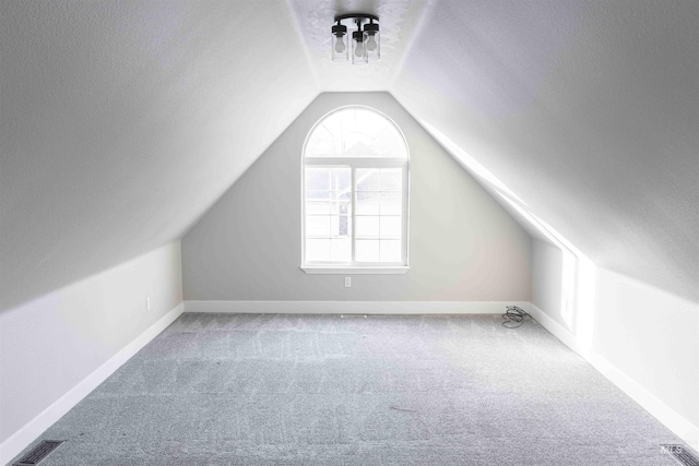 bonus room with lofted ceiling, a textured ceiling, and carpet floors