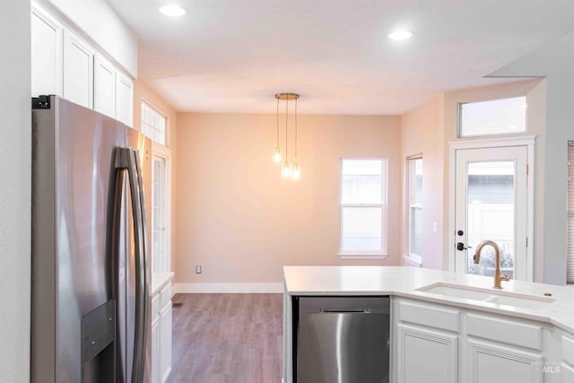 kitchen featuring appliances with stainless steel finishes, white cabinetry, pendant lighting, and sink