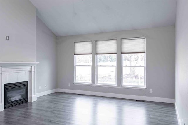 unfurnished living room featuring lofted ceiling, dark wood-type flooring, and a tile fireplace