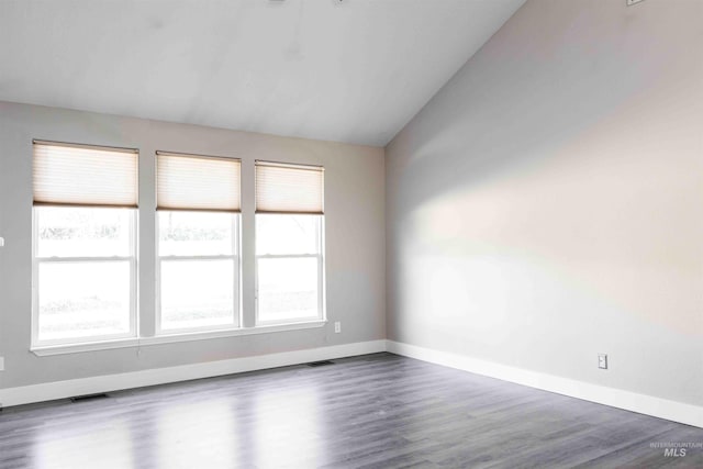 empty room with dark hardwood / wood-style flooring and vaulted ceiling