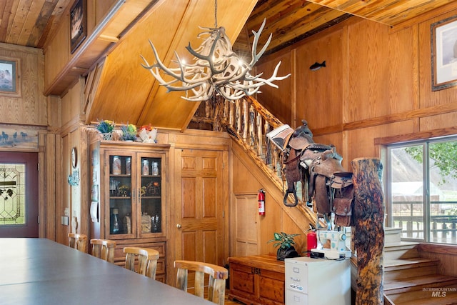 dining room featuring a chandelier, wooden ceiling, lofted ceiling, and wood walls