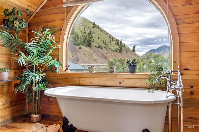 bathroom featuring vaulted ceiling, hardwood / wood-style flooring, wooden ceiling, wooden walls, and a mountain view