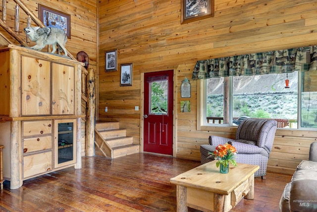 unfurnished living room featuring a high ceiling, wooden walls, and dark hardwood / wood-style flooring