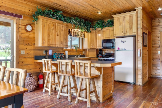 kitchen with a wealth of natural light, dark wood-type flooring, wooden walls, and white fridge