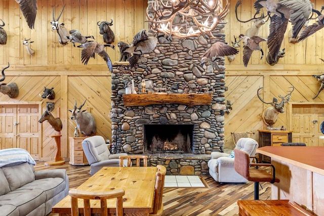 living room featuring a stone fireplace, hardwood / wood-style flooring, and wood walls