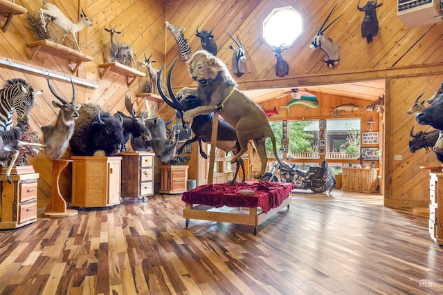 interior space with vaulted ceiling with beams, wooden walls, and hardwood / wood-style flooring